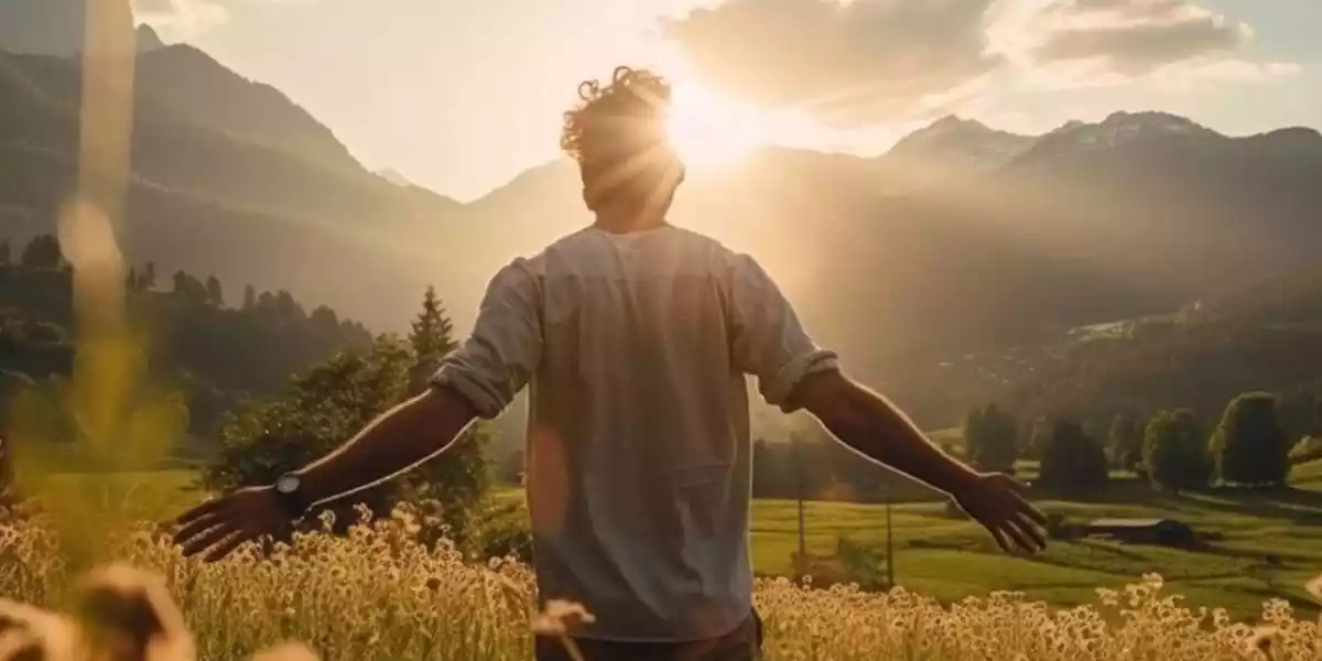 Man standing in a field with arms open to the sun, symbolizing freedom and abundance